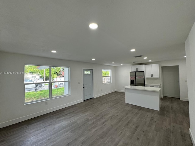 kitchen with stainless steel fridge with ice dispenser, dark hardwood / wood-style floors, white cabinets, and a center island