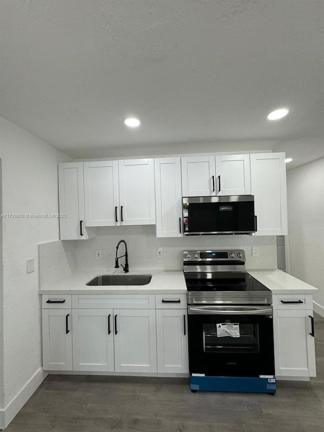 kitchen featuring stainless steel electric range oven, white cabinetry, sink, dark hardwood / wood-style flooring, and decorative backsplash