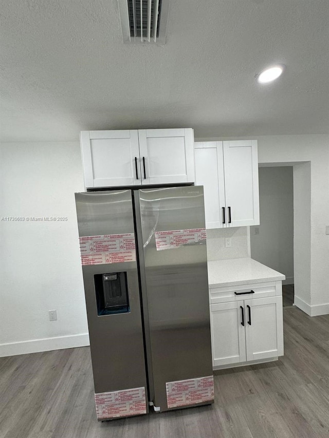 kitchen featuring white cabinetry, stainless steel fridge, a textured ceiling, and hardwood / wood-style flooring