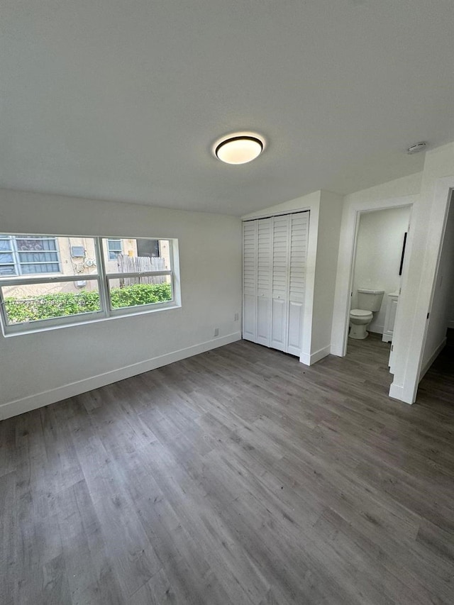 unfurnished bedroom featuring ensuite bathroom, hardwood / wood-style floors, and a closet