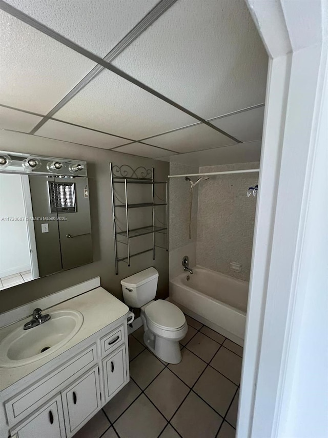 full bathroom featuring tiled shower / bath combo, a paneled ceiling, tile patterned floors, vanity, and toilet