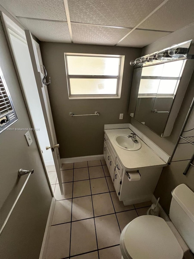 bathroom featuring a paneled ceiling, toilet, tile patterned flooring, and vanity