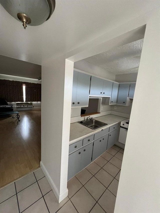 kitchen with a textured ceiling, white electric range, sink, light tile patterned floors, and gray cabinetry