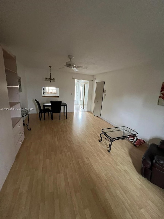 interior space featuring light hardwood / wood-style floors and ceiling fan with notable chandelier