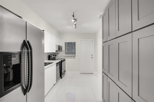 kitchen with gray cabinetry, stainless steel appliances, tasteful backsplash, track lighting, and light tile patterned flooring