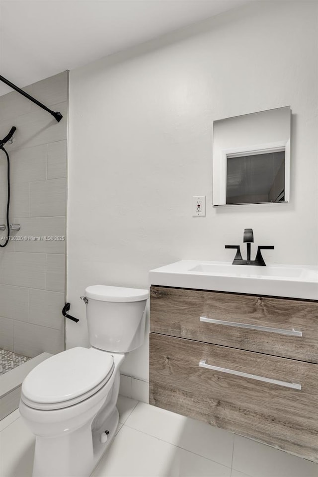 bathroom featuring vanity, tile patterned flooring, toilet, and tiled shower