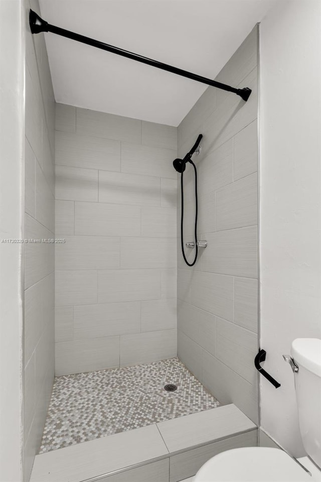 bathroom with a tile shower and toilet