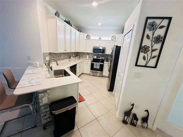 kitchen with sink, light tile patterned floors, stainless steel appliances, white cabinets, and decorative backsplash