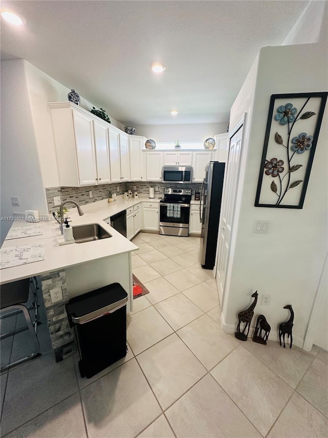 kitchen featuring appliances with stainless steel finishes, white cabinetry, sink, backsplash, and light tile patterned floors