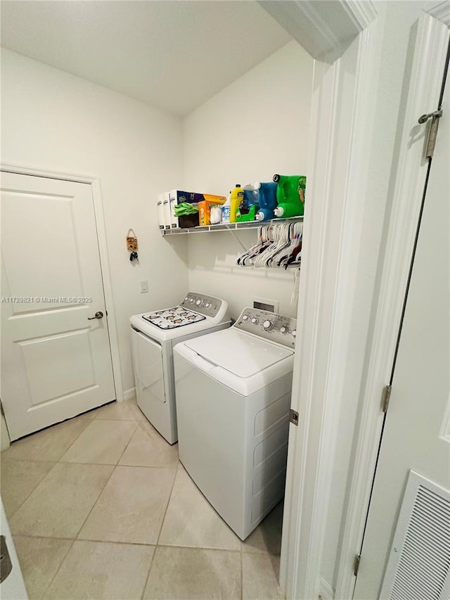 clothes washing area featuring separate washer and dryer and light tile patterned floors