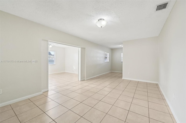 spare room featuring a wealth of natural light, light tile patterned floors, and a textured ceiling