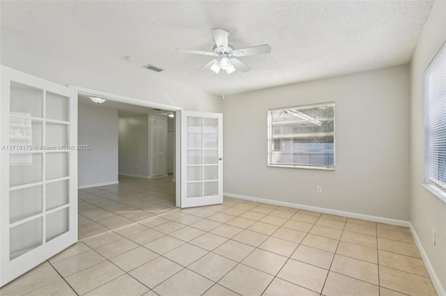 unfurnished room featuring ceiling fan, french doors, light tile patterned floors, and a textured ceiling