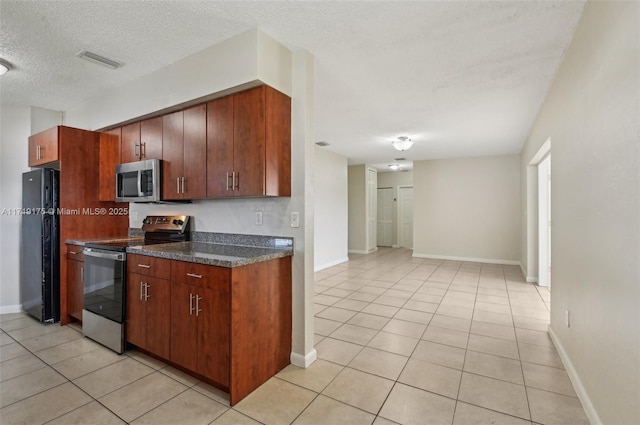 kitchen with a textured ceiling, light tile patterned floors, and stainless steel appliances