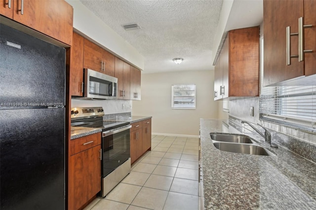 kitchen featuring a textured ceiling, appliances with stainless steel finishes, a wealth of natural light, sink, and light tile patterned floors