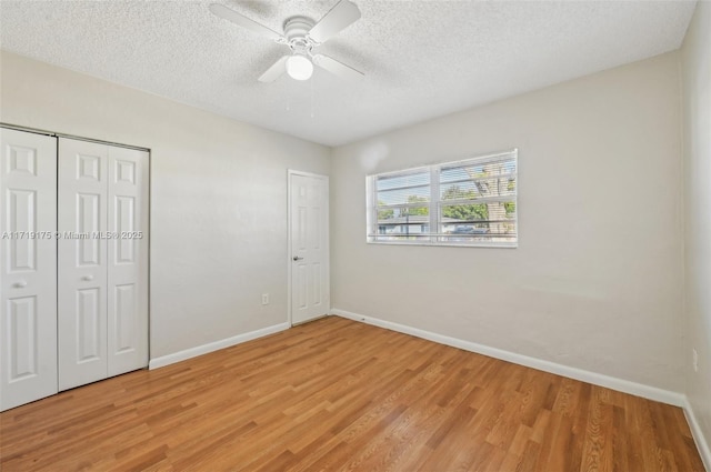 unfurnished bedroom with light hardwood / wood-style floors, a textured ceiling, a closet, and ceiling fan