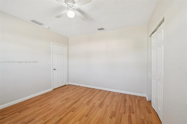 empty room with light wood-type flooring, a textured ceiling, and ceiling fan