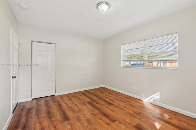 empty room featuring dark wood-type flooring and a textured ceiling