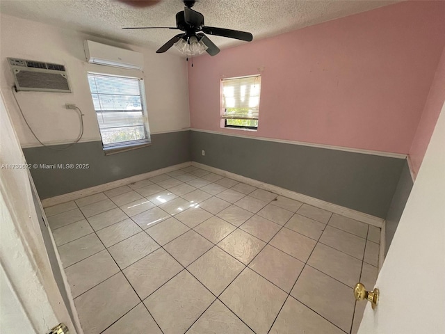 tiled spare room featuring a textured ceiling, plenty of natural light, and a wall mounted air conditioner