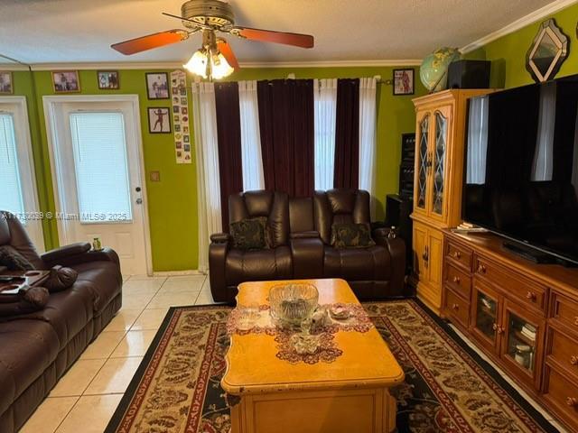 tiled living room featuring crown molding, a textured ceiling, and ceiling fan