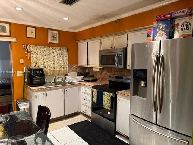 kitchen with sink, light tile patterned floors, a textured ceiling, decorative backsplash, and stainless steel appliances