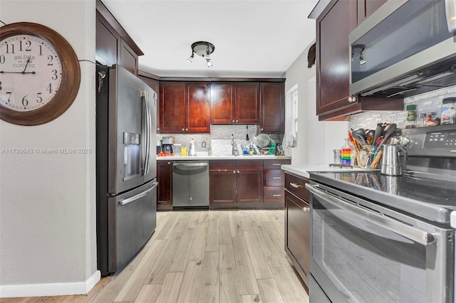 kitchen with sink, light wood-type flooring, stainless steel appliances, and backsplash