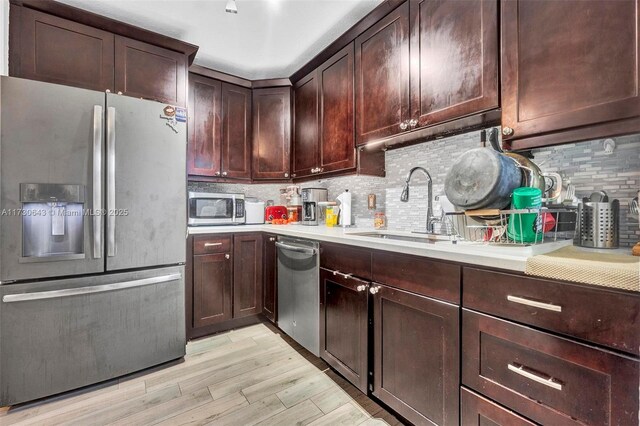 kitchen featuring light hardwood / wood-style floors, appliances with stainless steel finishes, decorative backsplash, and sink