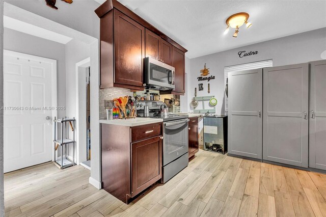 kitchen with dark brown cabinetry, appliances with stainless steel finishes, decorative backsplash, sink, and light hardwood / wood-style flooring