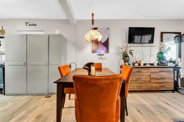 dining room featuring light wood-type flooring and beamed ceiling