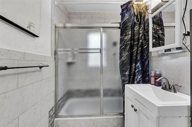 bathroom with a textured ceiling, tile walls, vanity, and enclosed tub / shower combo