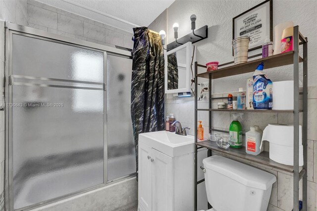 bathroom featuring tile walls, shower / bath combination with glass door, and vanity