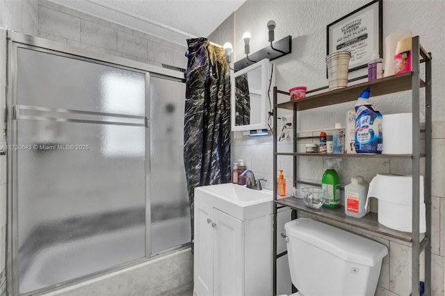 full bathroom with tile walls, toilet, vanity, and shower / bath combination with glass door