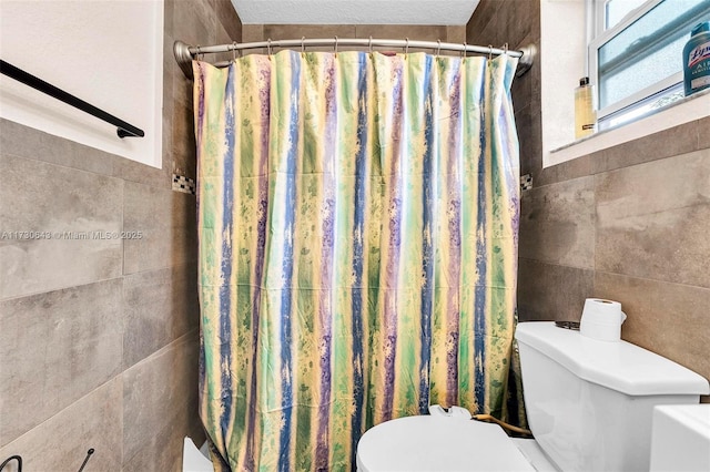 bathroom featuring toilet, tile walls, and curtained shower