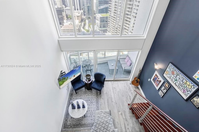 living room with a view of city, a high ceiling, wood finished floors, and baseboards