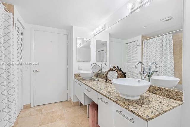 full bathroom featuring a closet, visible vents, a sink, and double vanity