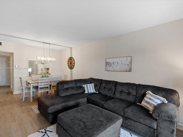 living room with light wood-type flooring and an inviting chandelier