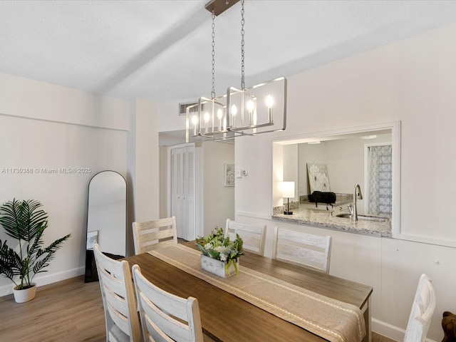 dining area with sink, light hardwood / wood-style flooring, and a textured ceiling