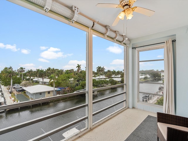 sunroom featuring a water view and ceiling fan