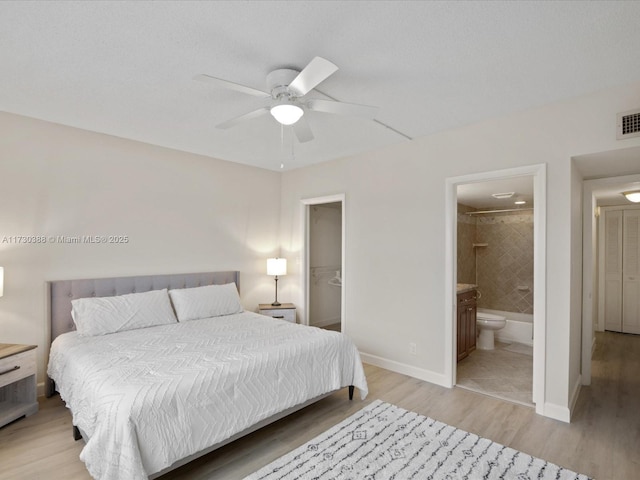 bedroom featuring ceiling fan, ensuite bathroom, and light hardwood / wood-style flooring