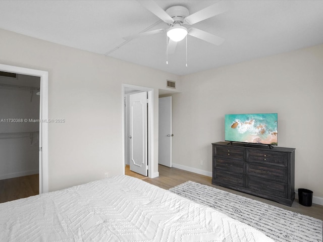 bedroom featuring ceiling fan, a spacious closet, and light hardwood / wood-style flooring