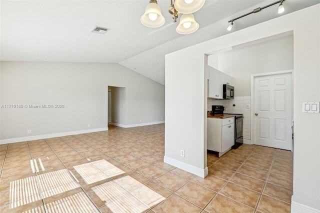 interior space with light tile patterned floors, vaulted ceiling, and a notable chandelier