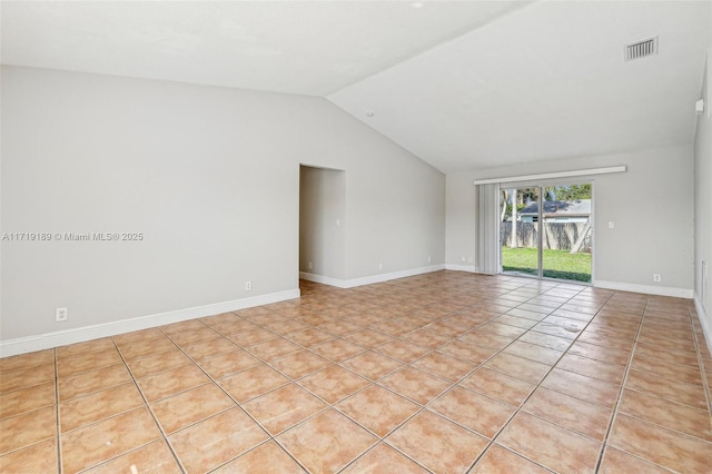 tiled spare room featuring vaulted ceiling