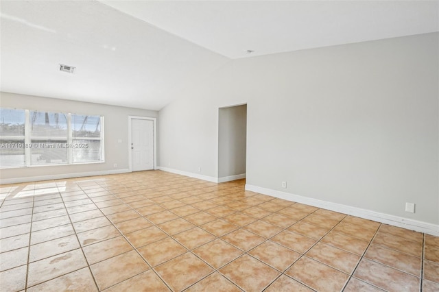 tiled empty room featuring vaulted ceiling