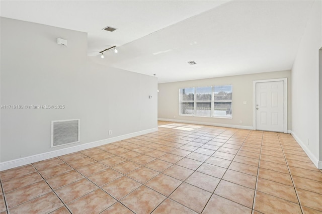 empty room with rail lighting and light tile patterned flooring