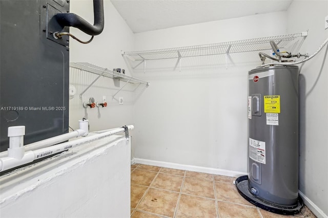 laundry room with light tile patterned floors and water heater