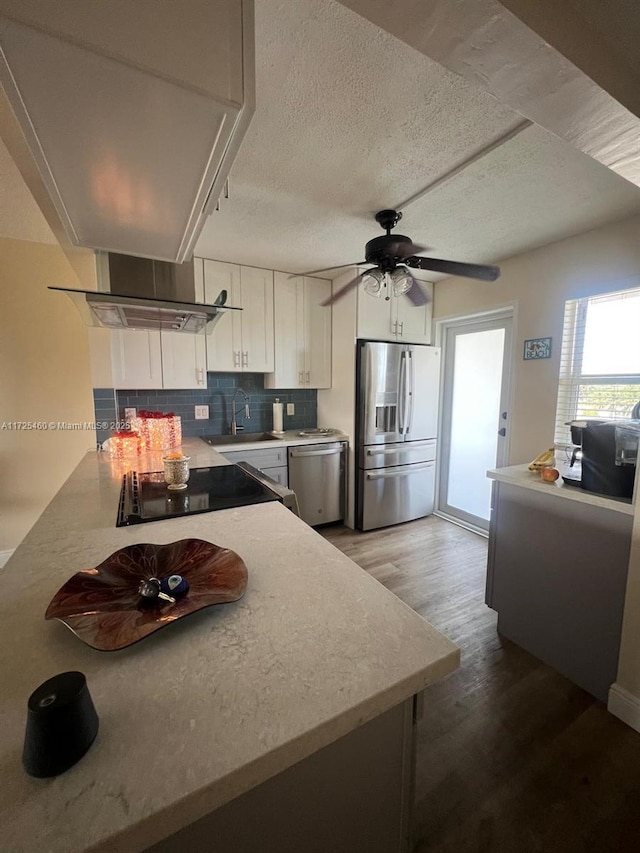 kitchen featuring hardwood / wood-style floors, white cabinetry, stainless steel appliances, decorative backsplash, and sink