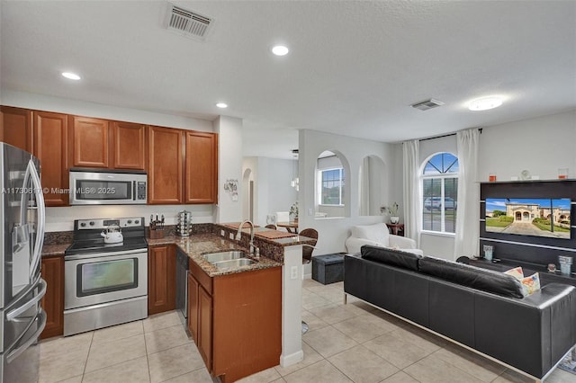 kitchen with sink, kitchen peninsula, light tile patterned floors, and stainless steel appliances