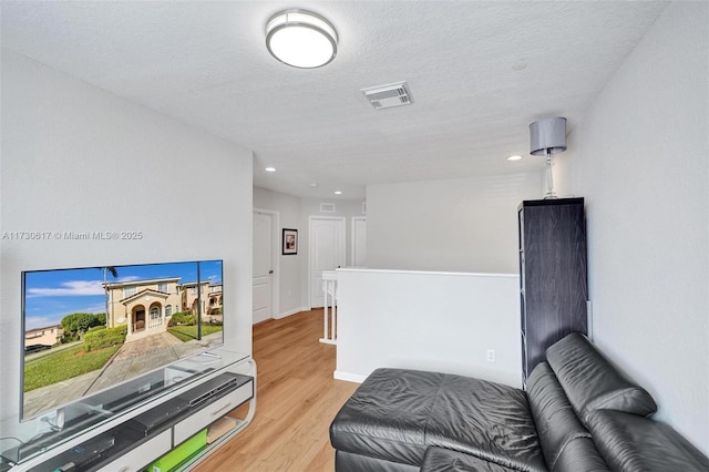 living area featuring light hardwood / wood-style flooring and a textured ceiling