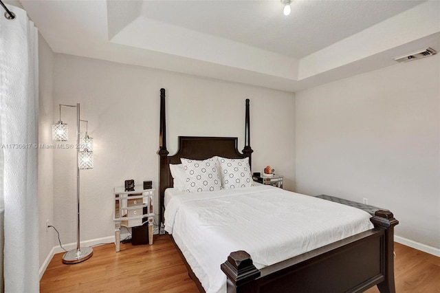 bedroom with hardwood / wood-style flooring and a raised ceiling