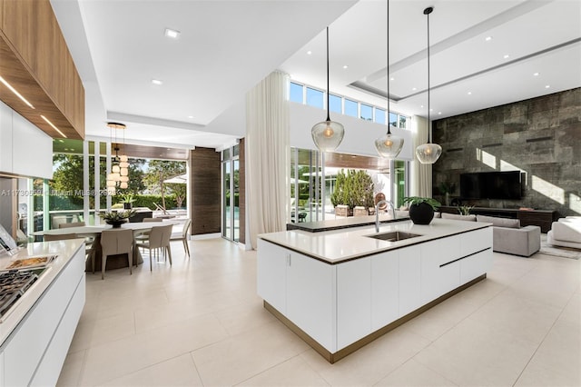 kitchen featuring sink, pendant lighting, white cabinets, and a center island with sink