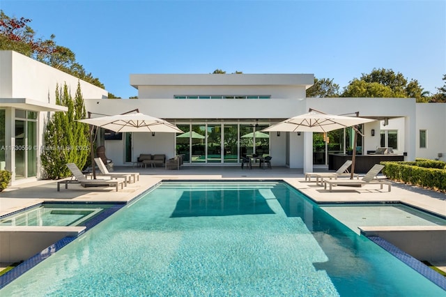 back of property featuring a swimming pool with hot tub and a patio